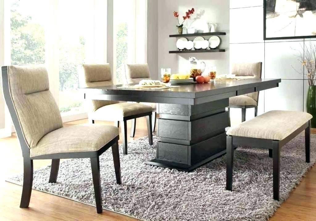 Dining room with dark wood table set, beige upholstered chairs and bench, place settings with fruit, shelving with plates